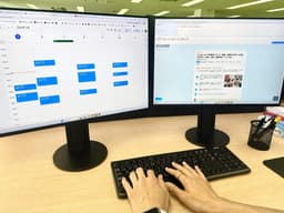 デュアルモニターでPC作業をするスタッフ